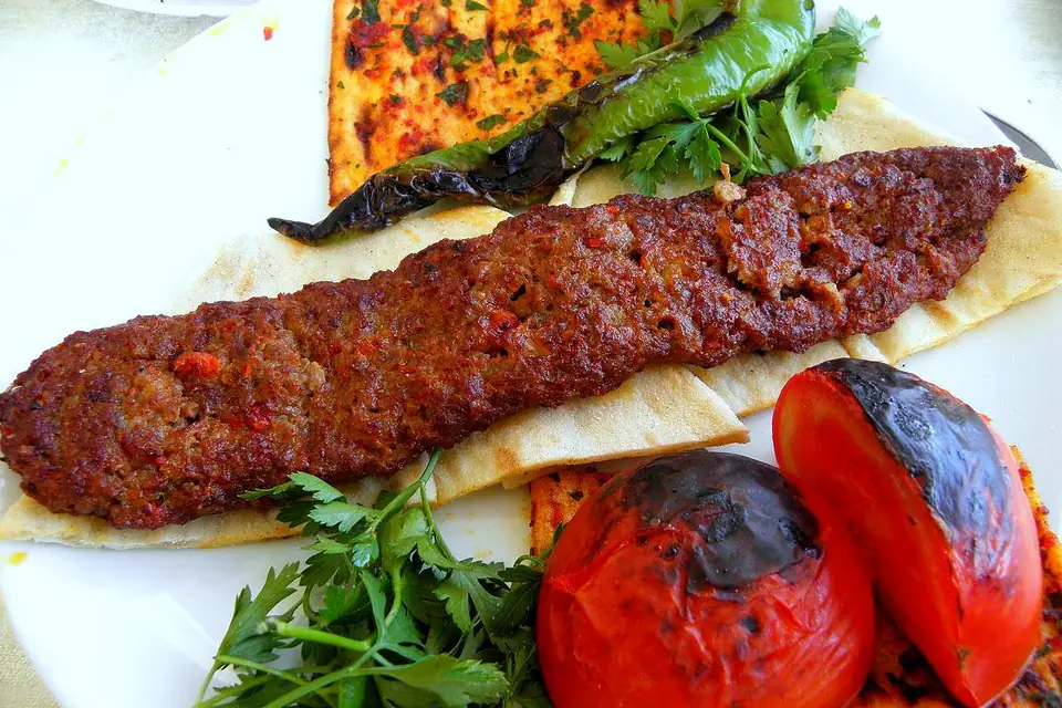 Adana kebab on lavash with roasted tomatoes and greens