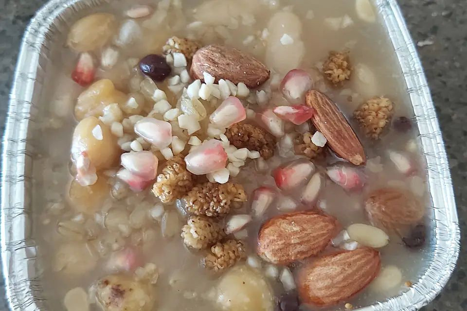 Aşure topped with almonds, pomegranate seeds and nuts