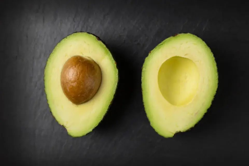 An avocado cut in half on a dark background