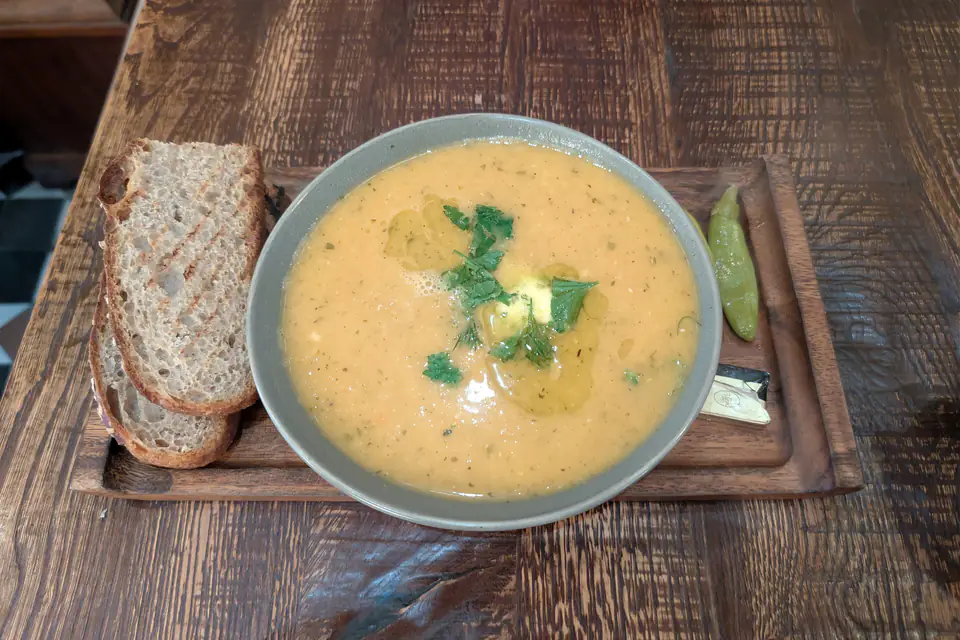A bowl of lentil soup with bread on the side