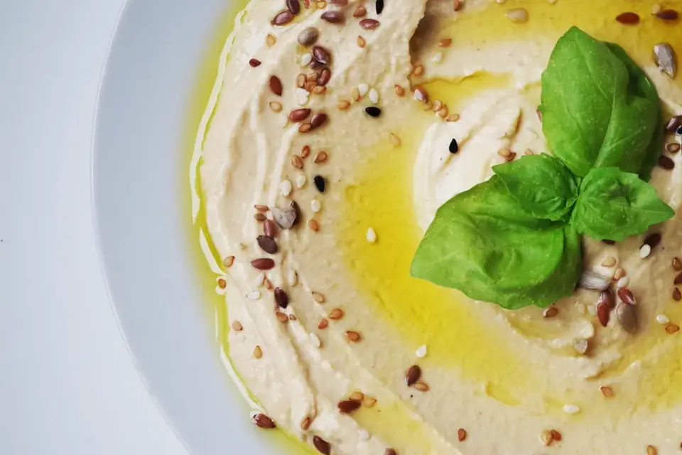 Hummus with olive oil, sesame seeds and basil