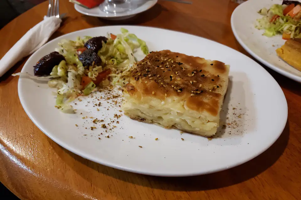 A slice of börek on a plate with salad