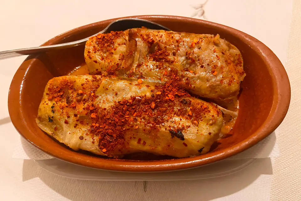 Stuffed cabbage rolls with red pepper flakes in a clay dish