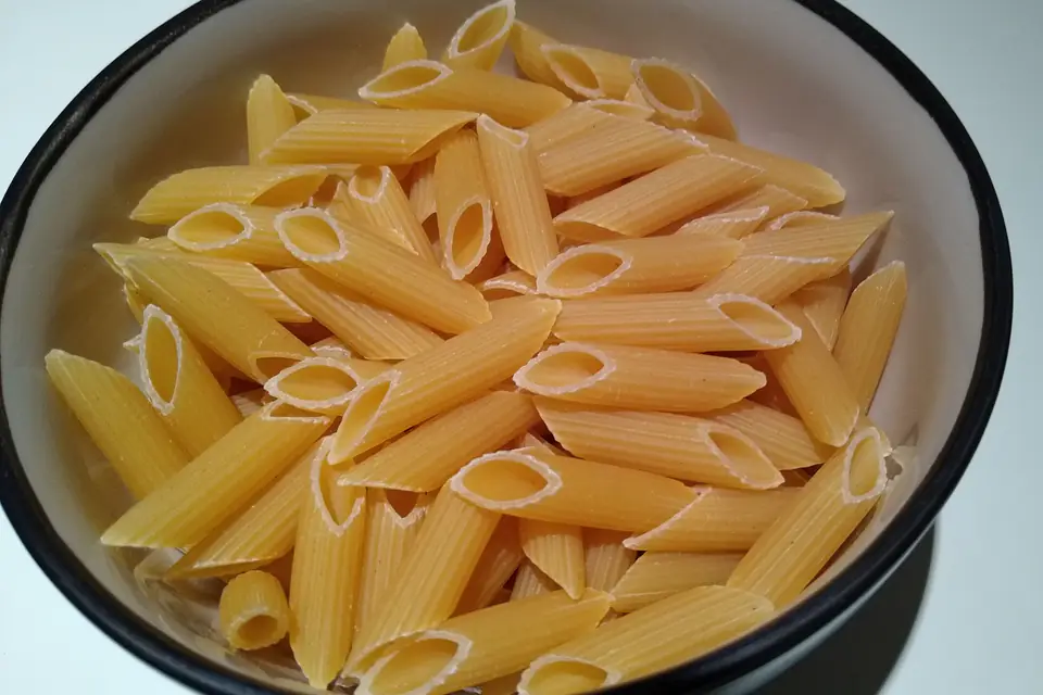 Raw penne pasta in a bowl