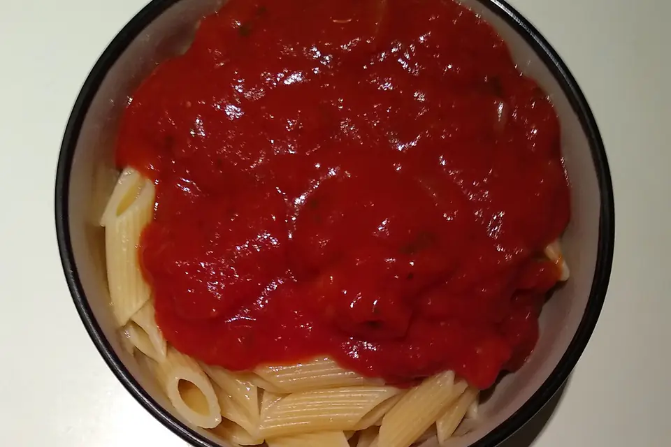 Penne with tomato sauce in a black bowl