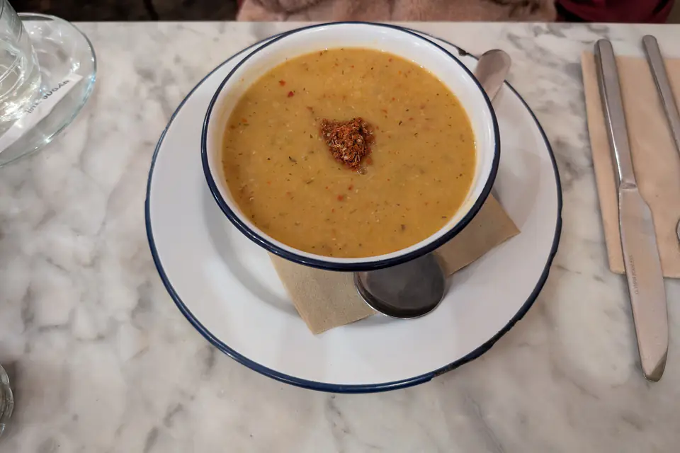 A bowl of lentil soup drizzled with red pepper butter