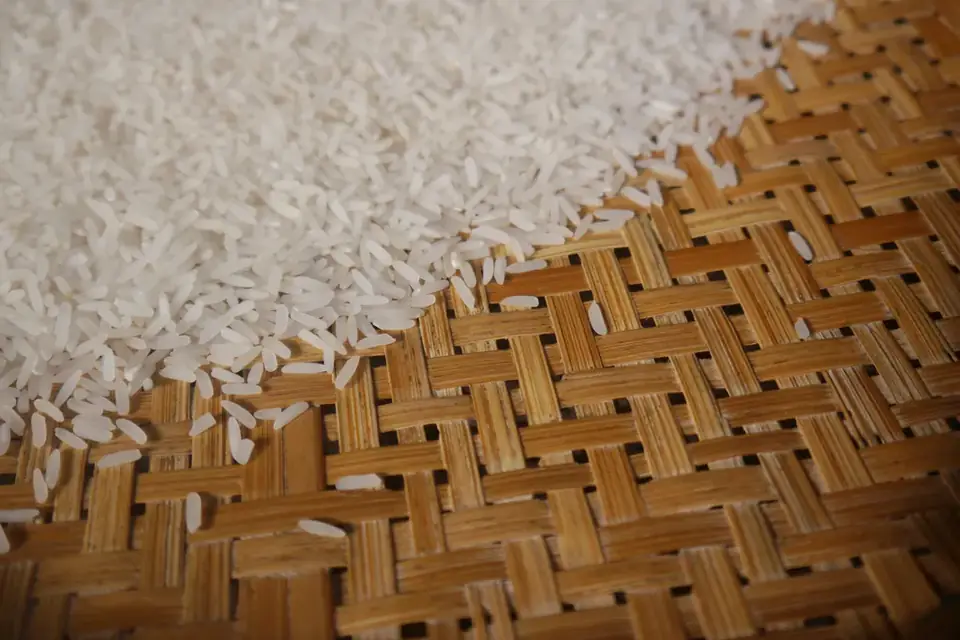 Raw white rice grains on a straw mat