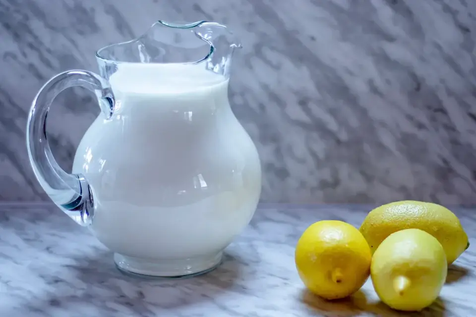 Milk in a glass jug with lemons beside it