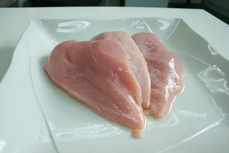 Raw chicken breast fillets on a white plate