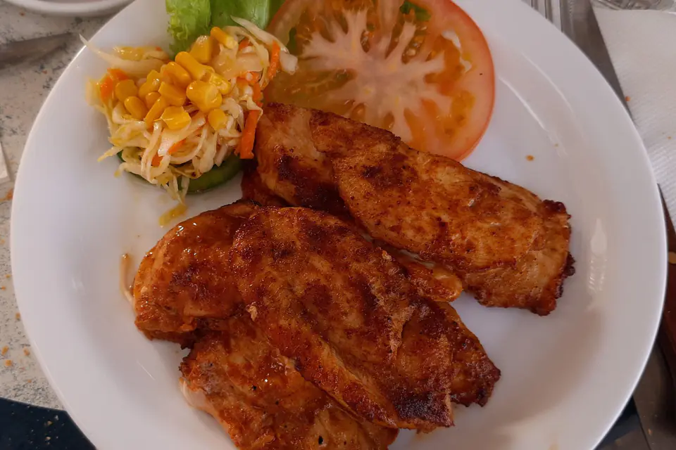 Grilled chicken breast with tomatoes and salad on a plate