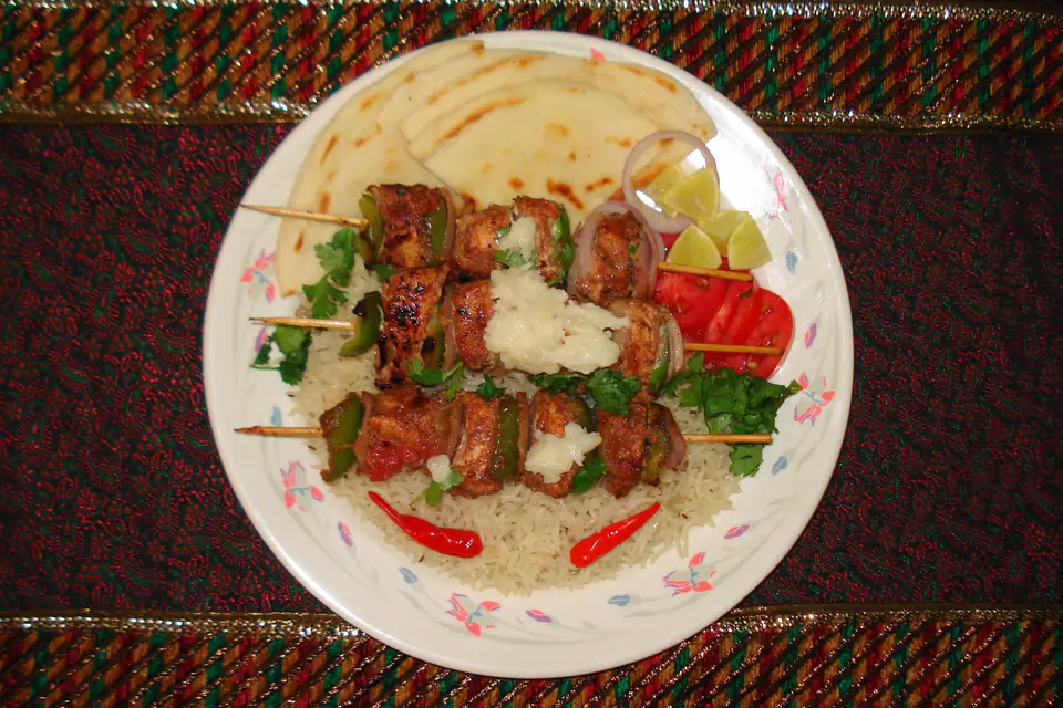 Chicken shish kebab on rice with tomatoes and greens