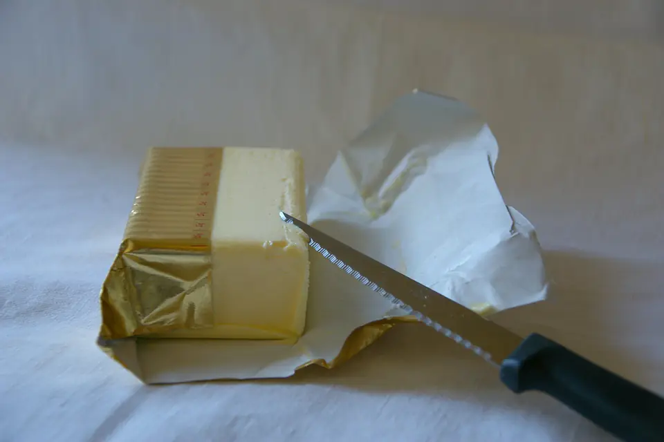 A block of butter in its opened wrapper with a knife