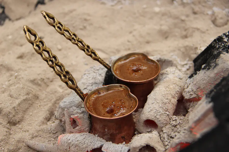Turkish coffee brewing in copper pots over embers