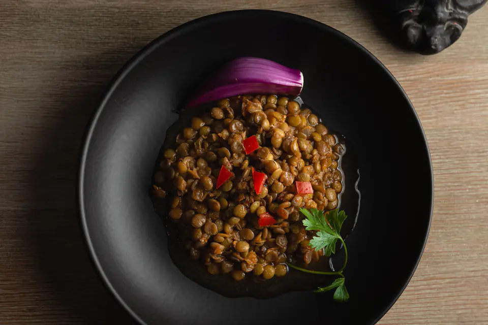 Green lentils with onion and parsley in a black bowl