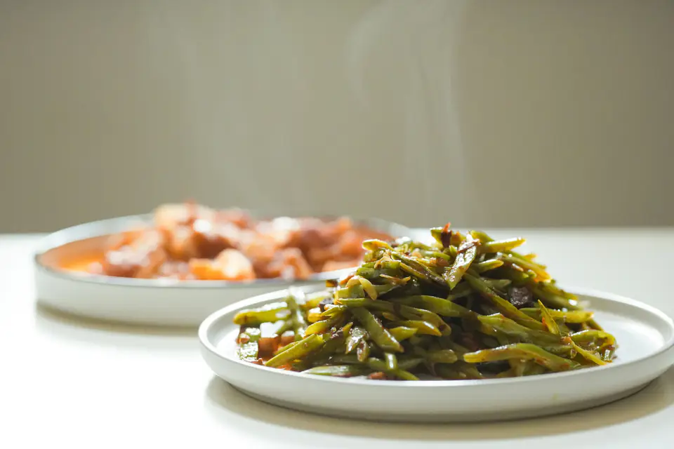 Steaming green beans in olive oil on a plate